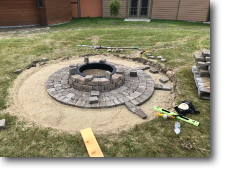 The fire pit is in place, and the layout of the patio pavers began.