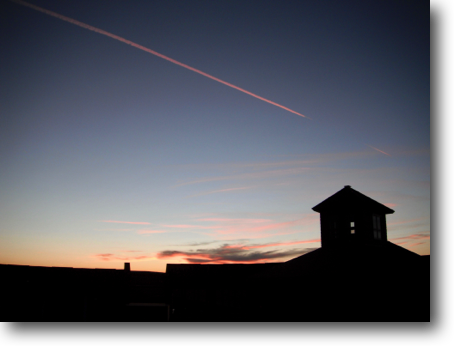 A lone contrail streaking across the early evening sky.