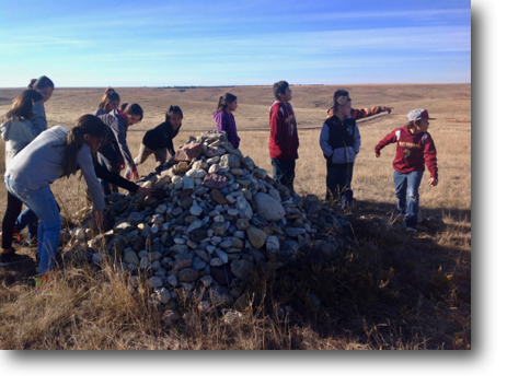 Fourth-graders from Crazy Horse School putting their rocks on the cairn.
