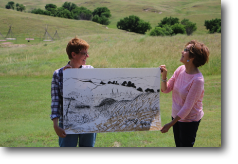 Fran and Andrea displaying Andrea's drawing in front of the landscape in it.